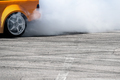 yellow sport car drifting on gray speed tarmac track with smoke coming out of the back tire wheel - PhotoDune Item for Sale
