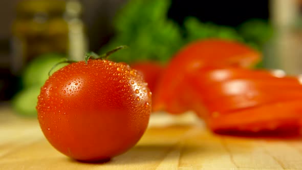 Single freshly harvested tomato in front of cucumber, tomato and green lettuce in the background