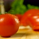 Single freshly harvested tomato in front of cucumber, tomato and green lettuce in the background - VideoHive Item for Sale