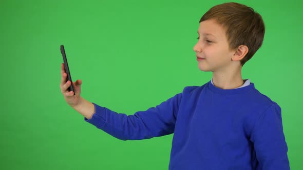 A Young Cute Boy Takes Selfies with a Smartphone - Green Screen Studio