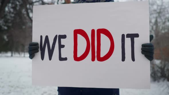 A man stands with a banner. We did it. Message shows attitude of the election.