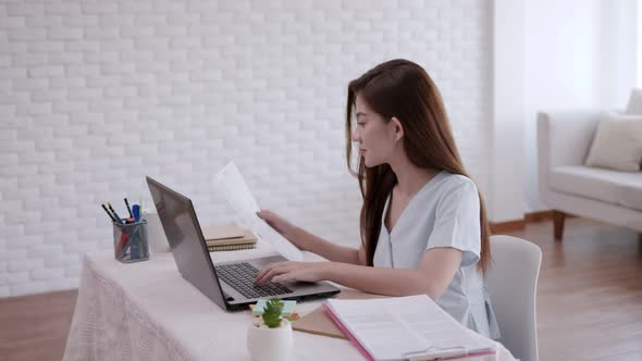 Business Asian woman type note job on laptop in living room.Work from home.