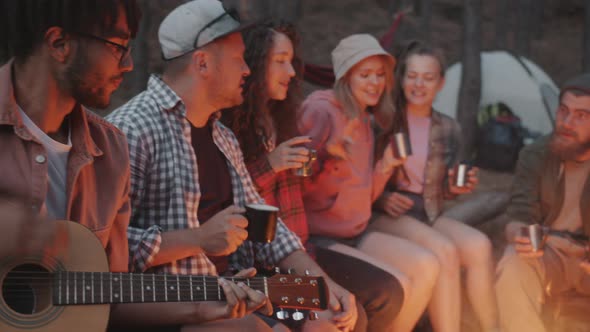 Playful Youth Singing to Guitar Dancing Drinking From Metal Cups in Dark Autumn Forest Sitting