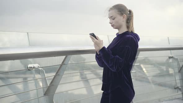 Side View Portrait of Beautiful Sportswoman Using Smartphone Outdoors