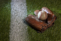Old baseball in brown leather mitt on a grass field with a white stripe - PhotoDune Item for Sale