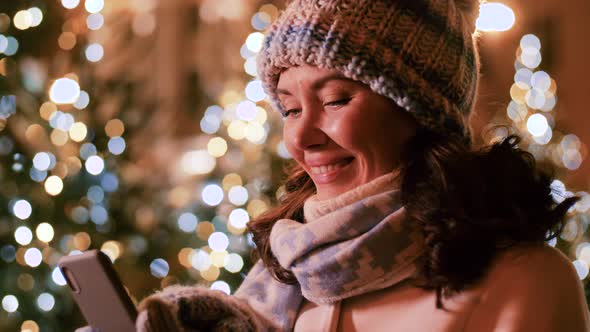 Happy Woman with Smartphone in Christmas City