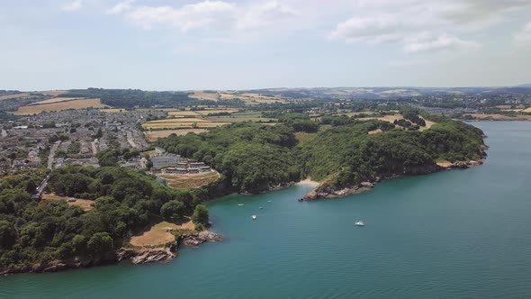 Panorama sky view of beach in Brixham England. Flying over coastal town with harbour and lighthouse.