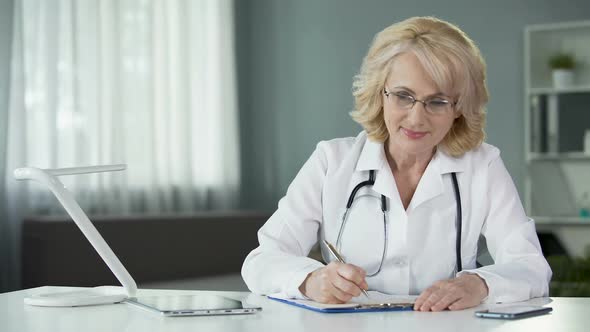Female Physician Making Prescriptions Filling out Patients Medical Records