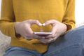 Close up of a woman's hands in yellow sweater using a mobile phone - PhotoDune Item for Sale
