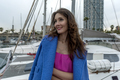Beautiful woman in pink dress and blue jacket posing on a sailboat in a city harbor on a cloudy day. - PhotoDune Item for Sale