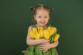 Comely girl in green dress is hugging bouquet of tulips as gift to mother - PhotoDune Item for Sale