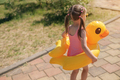 Girl in swimsuit with circle of a duck goes on way to beach to lake to swim - PhotoDune Item for Sale