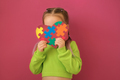 Shy child with autism syndrome hides behind heart decorated with colorful puzzle - PhotoDune Item for Sale