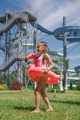 Girl with circle-flamingo stands at high structures of slides of water park - PhotoDune Item for Sale