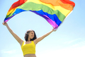 A happy woman holds a rainbow flag fluttering in the wind - PhotoDune Item for Sale