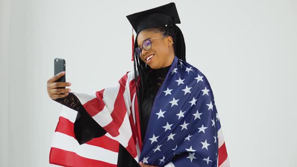 Happy Stylish Afro American Female Student in Graduate Uniform Taking Selfie Holding USA Flag on