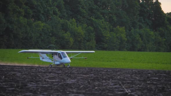 A Small Airplane Takes Off From a Field.at Sunrise