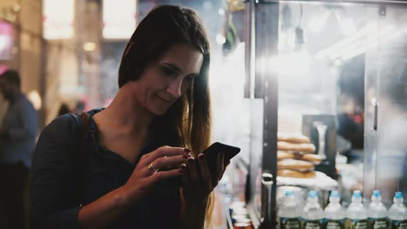 Happy Attractive Female CEO Using Smartphone E-commerce App Near Steaming Street Food Vendor