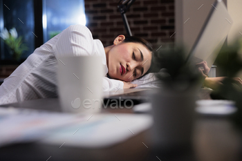 resting at work because of overwork. Tired fatigued businesswoman sleeping on desk in office workspace after overtime work