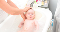 Adorable baby girl in bath with mother. Looking up with big brown eyes and smiling. Copy space - PhotoDune Item for Sale