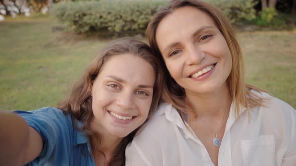 Two Women Laying on the Grass and Take a Selfie Photo Together