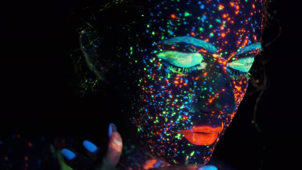 Portrait of a Young Woman in Ultraviolet Light. Face of the Model Is Painted with Glowing Colors