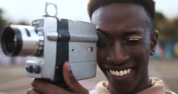 Young african man using vintage old video camera outdoor