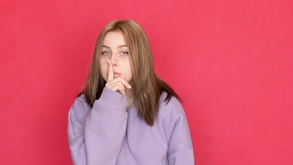 Caucasian young woman 20 years old shows a sign of silence with her finger, keep quiet, do not revea