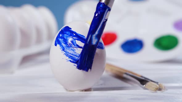 Painting Easter Eggs with a Blue Brush Preparation for Spring Holiday Religious Celebration Art