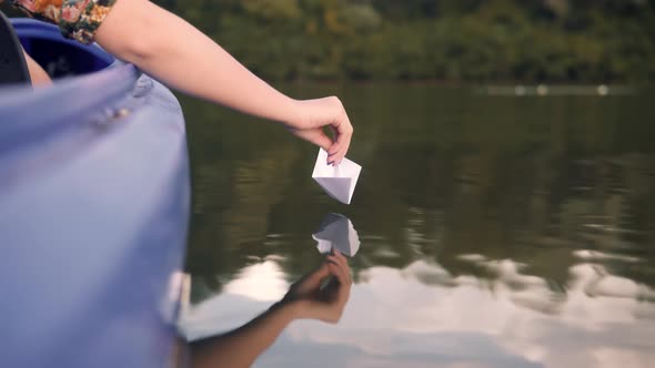 Girl Launching Origami Ship In Water On Sunset. Relaxing And Enjoying Time. Paper Boat On River.
