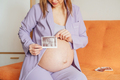 Pregnant woman holding and looking sonogram or ultrasonography picture of her unborn baby - PhotoDune Item for Sale