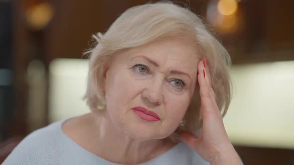 Closeup Portrait of Sad Wrinkled Caucasian Woman with Headache Migraine Touching Temples and