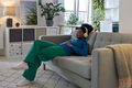 Happy relaxed African American woman in headphones closing eyes enjoying music sits on sofa - PhotoDune Item for Sale