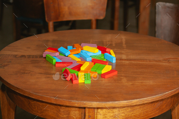 The ruined tower of Jenga game. Colored blocks scattered on table