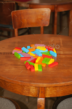 The ruined tower of Jenga game. Colored blocks scattered on table.