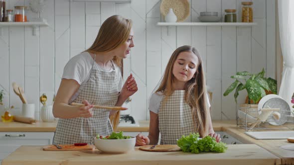Mother and Daughter Cook Natural Vegetable Salad Mommy Feeding Baby From Wooden Spoon Girl Eating