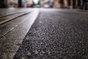 High angle shot of an asphalt road texture and a stone sidewalk