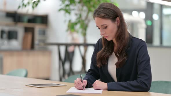 Young Businesswoman Writing on Paper at Work 