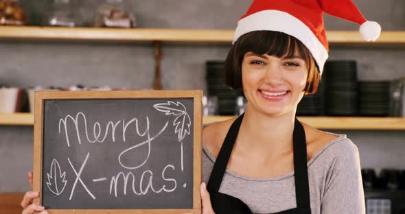 Portrait of waitress showing slate with merry x-mas sign