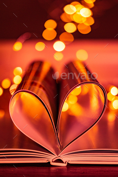 Vertical shot of a heart created with the pages of a book on a light bokeh background