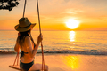 Sexy woman wear bikini and straw hat swing the swings at tropical beach on summer vacation at sunset - PhotoDune Item for Sale