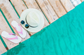 Top view of pink-white sandals, straw hat and sunglasses on wooden bridge over emerald green sea  - PhotoDune Item for Sale