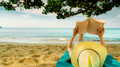 Woman lie down on green towel that put on sand beach under the tree and reading a book. Slow life - PhotoDune Item for Sale