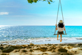 Asian woman in casual style wear hat swing the swings at sand beach and looking beautiful sea - PhotoDune Item for Sale
