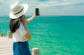 Young Asian woman wear hat in casual style use smartphone taking selfie at pier. Summer vacation - PhotoDune Item for Sale
