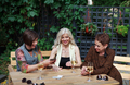 Mature female friends play card board game in cafe, have fun, laughing and drinking wine from bakals - PhotoDune Item for Sale
