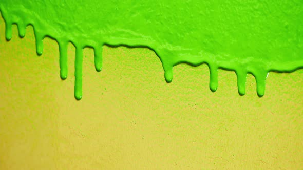 Green Neon Paint Dripping on Yellow Wall Closeup