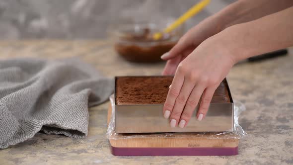 Hands Remove Metal Shape From a Chocolate Cake