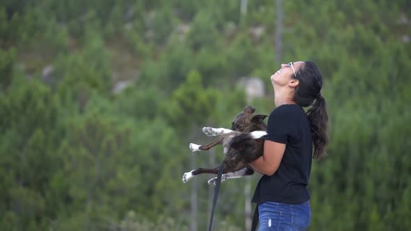 Woman having fun playing with a dog in slow motion in her arms on a wild beach landscape