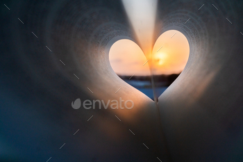 Book with heart-shaped pages against a beautiful sunset